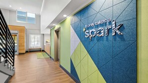 A modern hotel corridor with a geometric wall design and a sign that reads "It only takes a spark." - Spark by Hilton Woodbridge (Woodbridge)