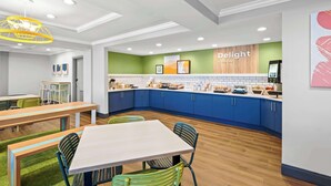 A modern kitchen with blue cabinets, a white countertop, and a green accent wall. - Spark by Hilton Woodbridge (Woodbridge)