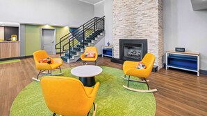 A lobby with a staircase, a fireplace, and a reception desk. - Spark by Hilton Woodbridge (Woodbridge)