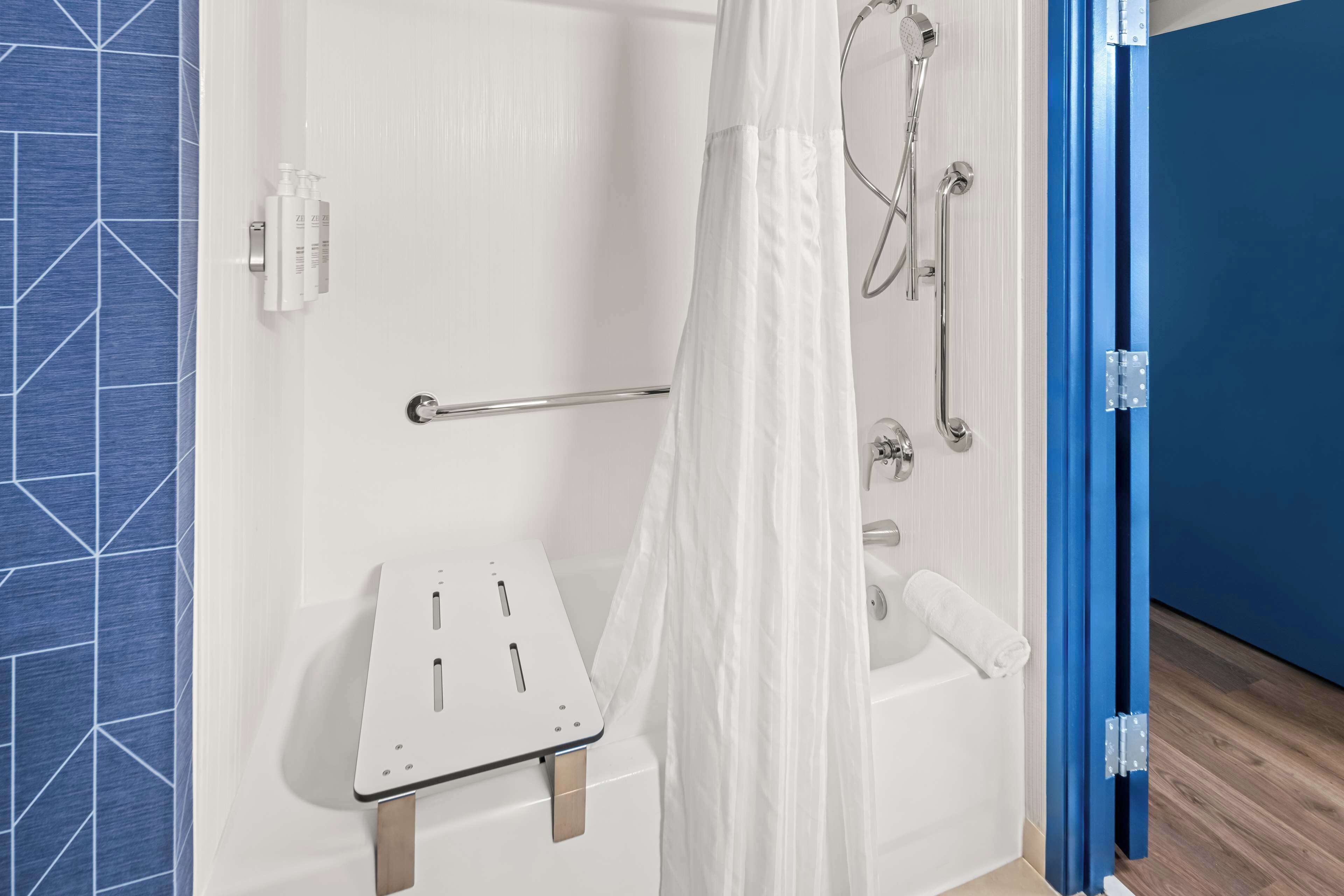 A modern bathroom with a shower, a white bathtub, and a shower curtain.