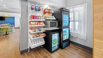 A compact kitchenette with a microwave, a mini-fridge, and a variety of snacks and beverages.