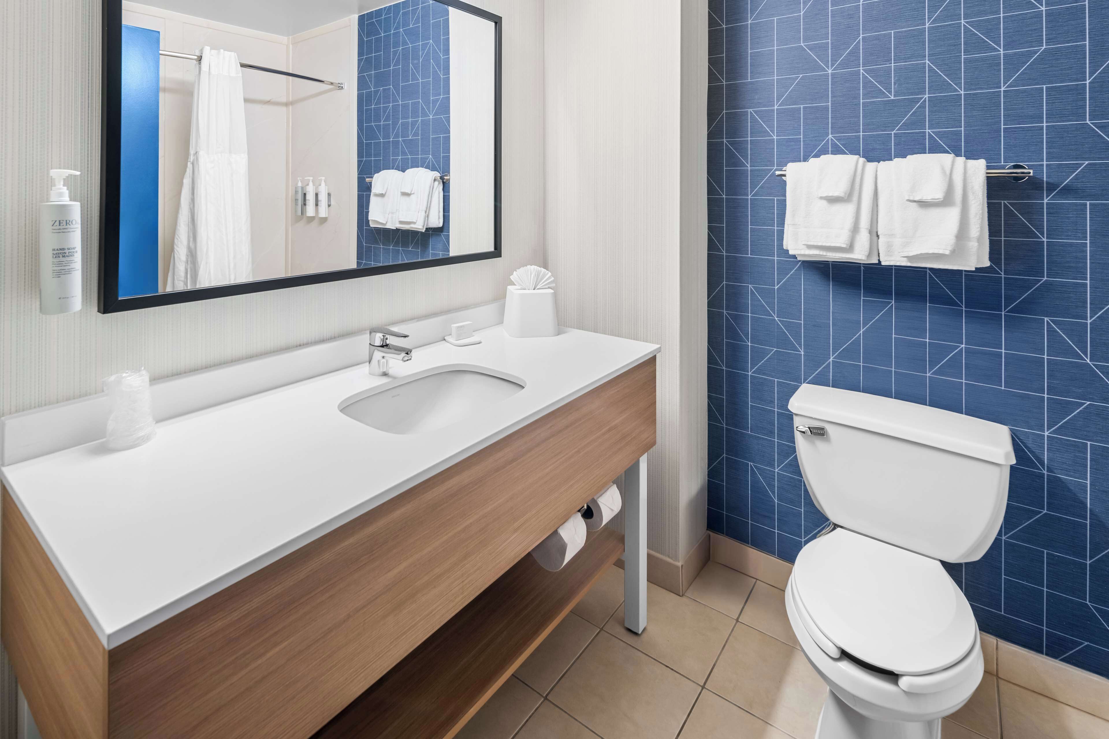 A modern bathroom with a white sink, mirror, and toilet.