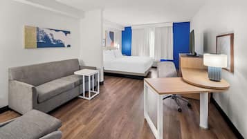 Ett hotellrum med en säng, en soffa, ett skrivbord och ett litet bord.