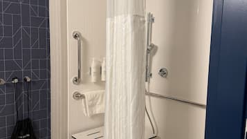 A modern shower area with a white shower curtain, a handheld showerhead, and a glass-enclosed shower stall.