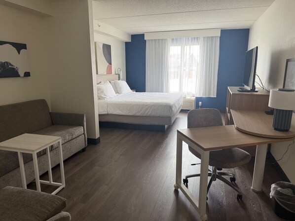 A hotel room with a bed, a sofa, a desk, and a chair. - Spark by Hilton Woodbridge (Woodbridge)