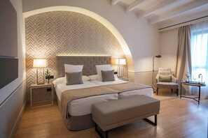 Une chambre d’hôtel moderne avec un grand lit, une banquette, une chaise et un bureau avec une lampe.