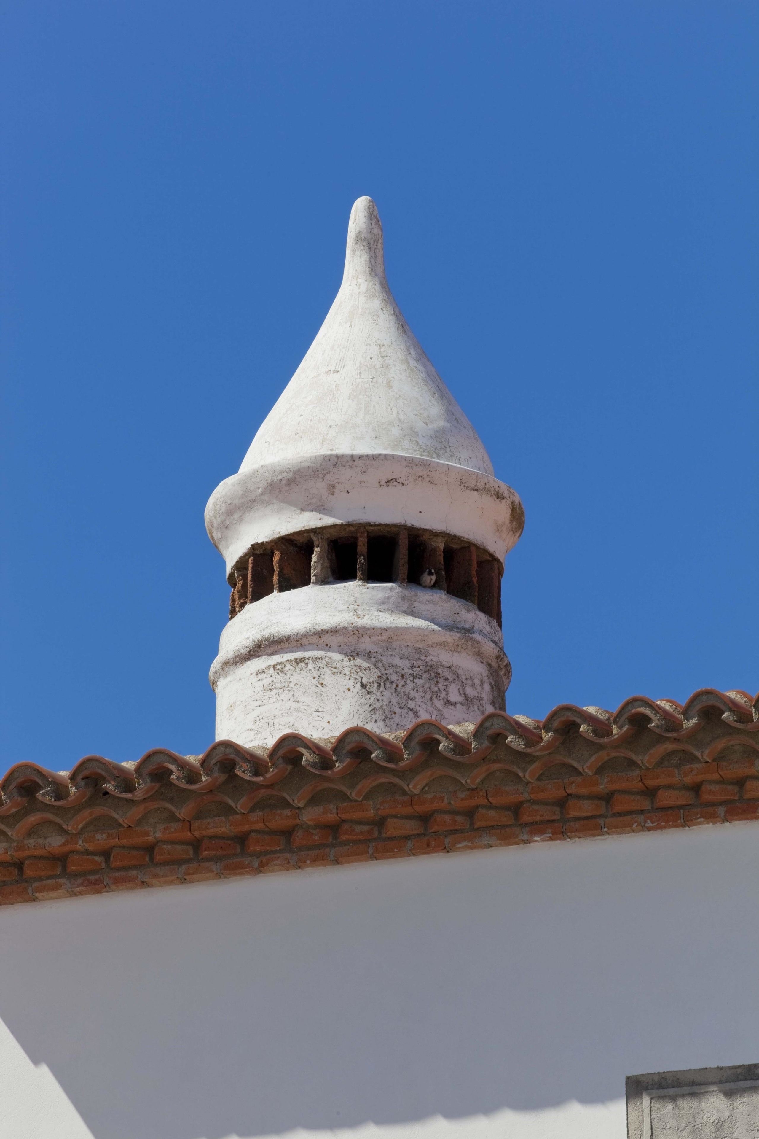A building with a conical roof and a tiled roof edge.