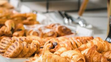 Een verscheidenheid aan gebak, waaronder croissants en ander gebakken lekkers, gepresenteerd op een toonbank.