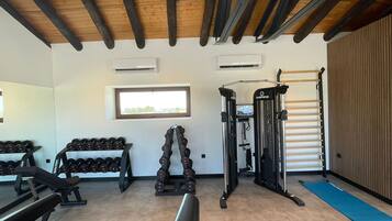 Un gimnasio con equipo de levantamiento de pesas, una banca y una barra para dominadas.