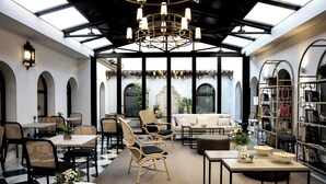A spacious indoor area with a high ceiling, a central chandelier, and a seating area with sofas and chairs. - Hotel Hospes Palacio de Arenales & Spa (Cáceres)