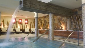 Een wellnessruimte met een jacuzzi, houten balken en een stenen muur.