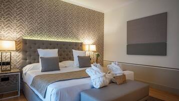 Una camera d'albergo moderna con un letto grande, due lampade da comodino, una testiera con motivo geometrico e un grande quadro astratto appeso alla parete.