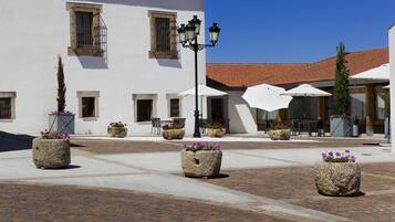 A courtyard with stone planters, outdoor seating, and a building with a tiled roof.