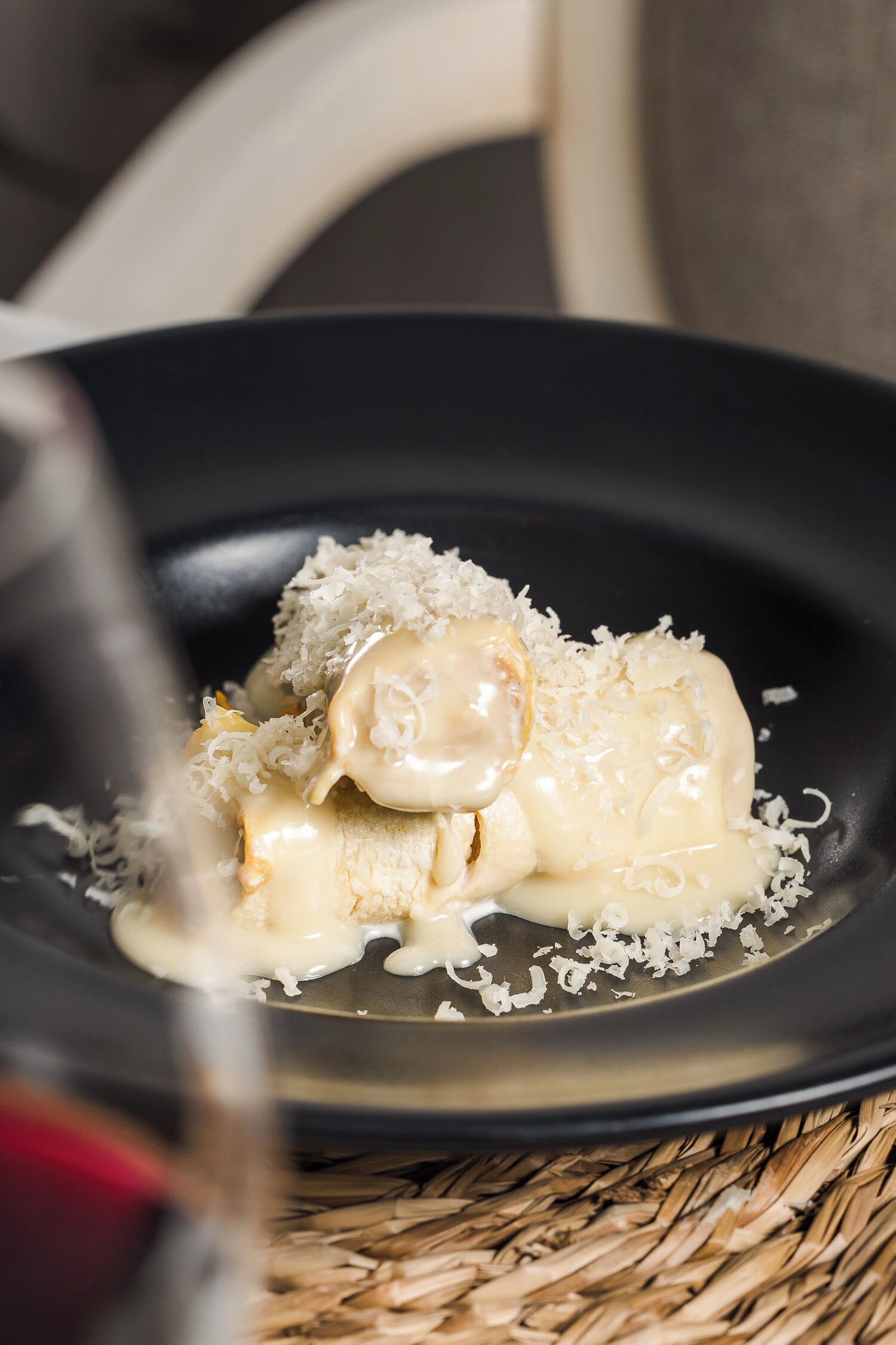 A dessert on a black plate with a woven mat underneath.