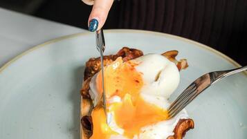Una persona cortando un plato de desayuno.