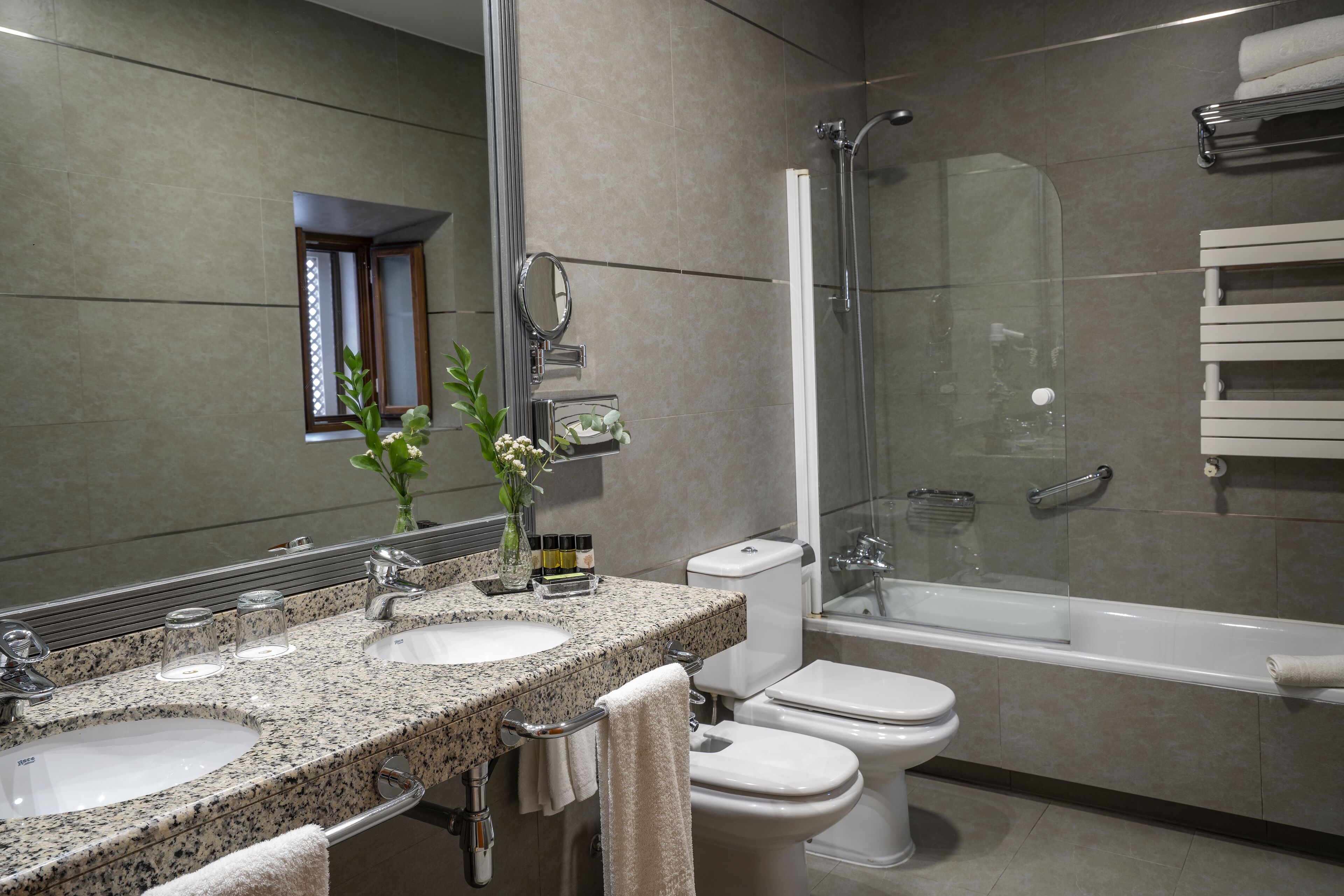 A modern bathroom with two sinks, a toilet, and a glass-enclosed shower.