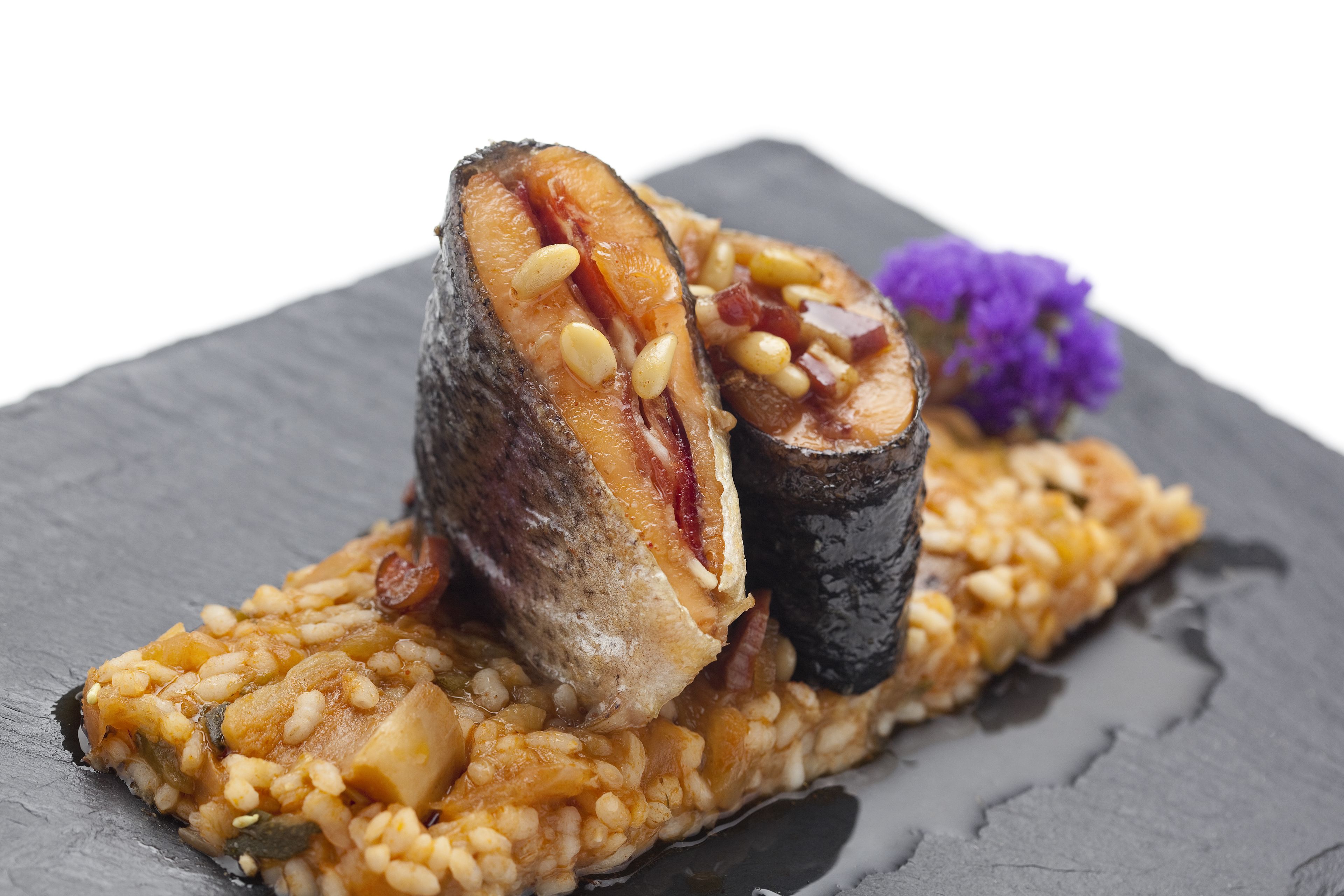 Un plato con una rebanada de carne, frijoles y un adorno sobre una fuente de pizarra.