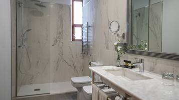 A modern bathroom with a glass-enclosed shower, a toilet, and a vanity with a large mirror.
