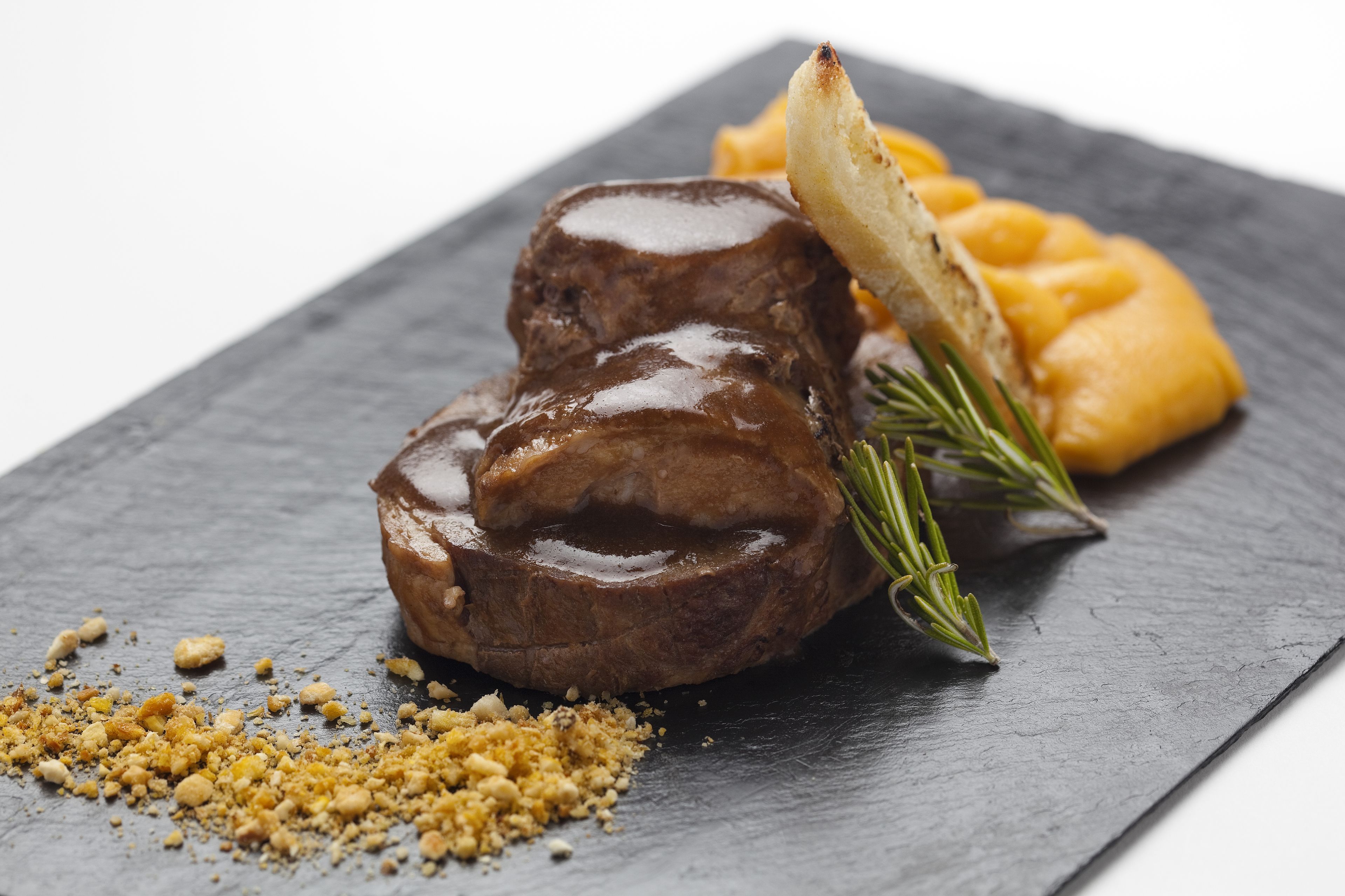 Un plato de carne con salsa y puré de papas sobre una losa de piedra.