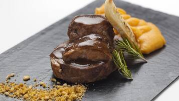 Un plato de carne con salsa y puré de papas sobre una losa de piedra.