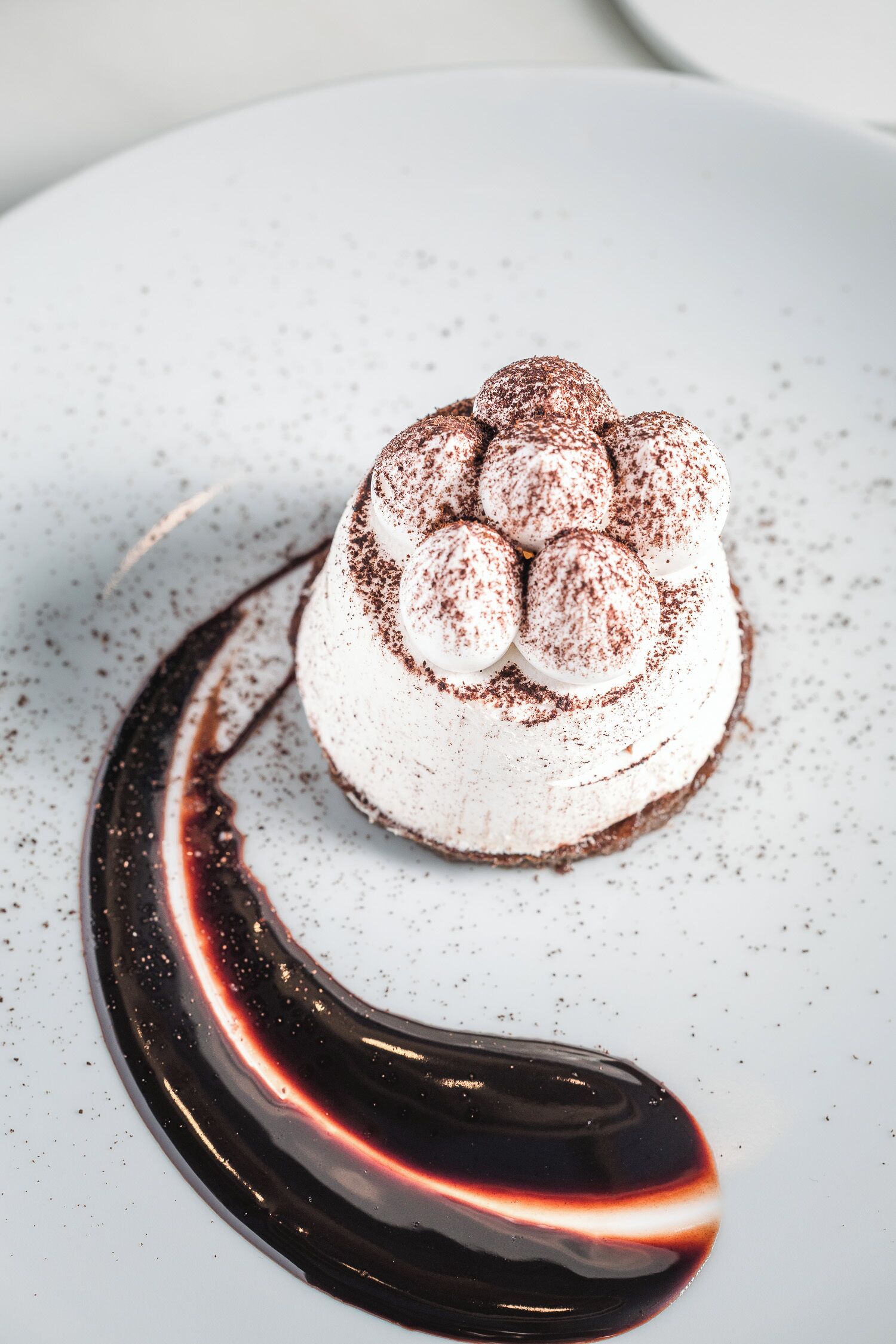 En dessert med vispad grädde och chokladströssel, serverad på en vit tallrik.