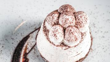 En dessert med vispad grädde och chokladströssel, serverad på en vit tallrik.