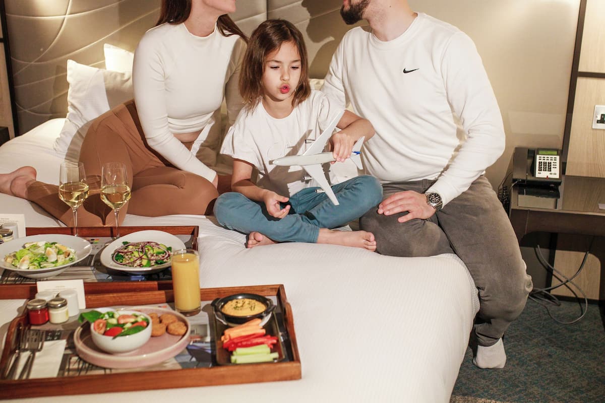 Une chambre d’hôtel avec un lit, une table de chevet, une lampe et un plateau avec de la nourriture et des boissons.