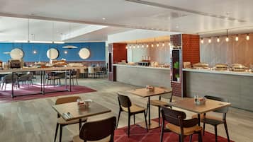 Un restaurante moderno con una barra larga, varias mesas y sillas.