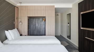 A modern hotel room with a large bed, a wardrobe, a mirror, and a television.