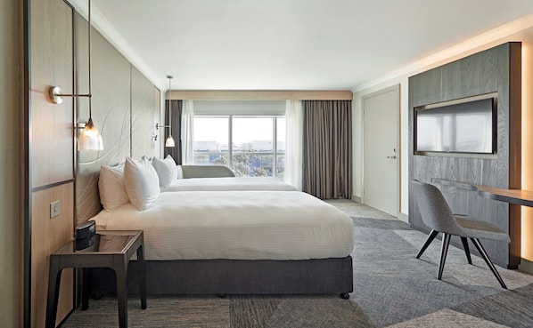A modern hotel room with a large bed, a desk, a chair, and a TV. - Hyatt Place London Heathrow Airport (West Drayton)