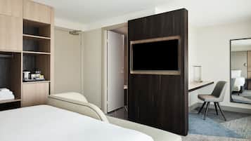 Una habitación de hotel con cama, escritorio, silla, televisor y armario.