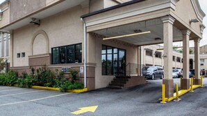 Un edificio con acceso cubierto, estacionamiento y un cartel de 'No dar la vuelta'.
