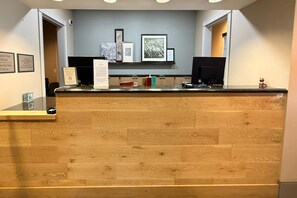 A reception desk with a wooden finish, a computer monitor, and a framed welcome sign. - Country Inn & Suites by Radisson, Lima (Lima)