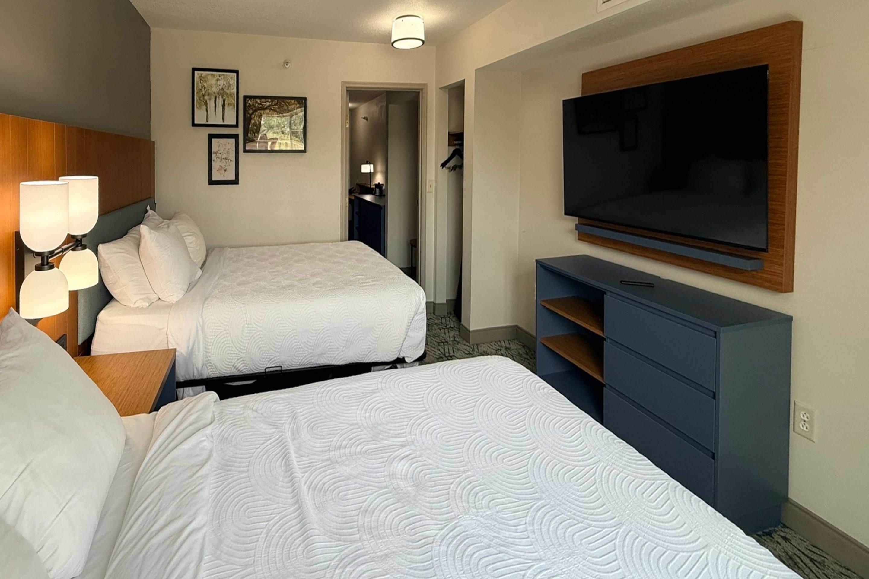 Een hotelkamer met twee bedden, een televisie, een bureau en een lamp.