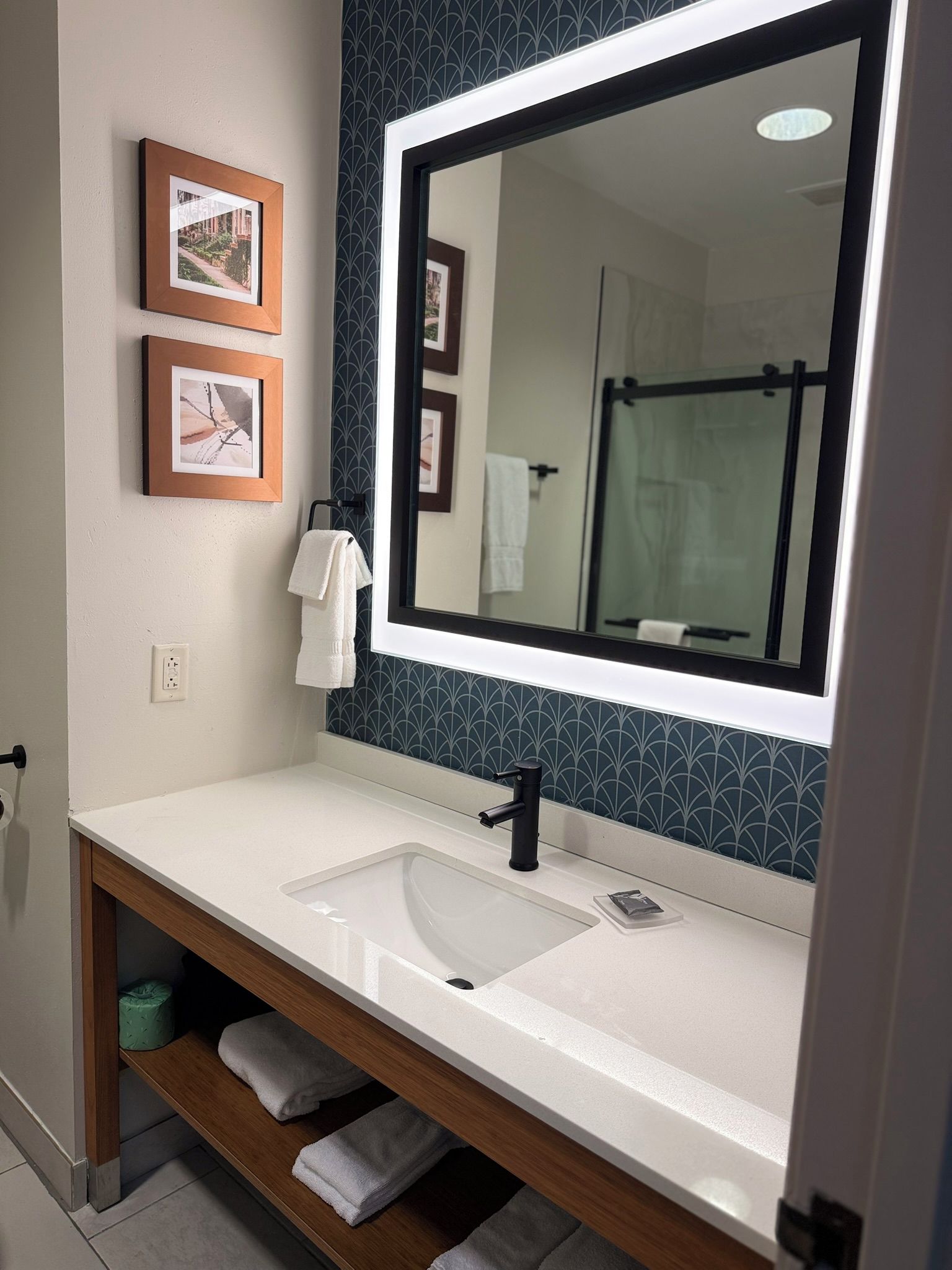 A bathroom with a white sink, a large mirror, and two framed pictures on the wall.