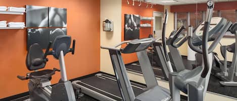 A gym with multiple treadmills, exercise bikes, and a mirrored wall.