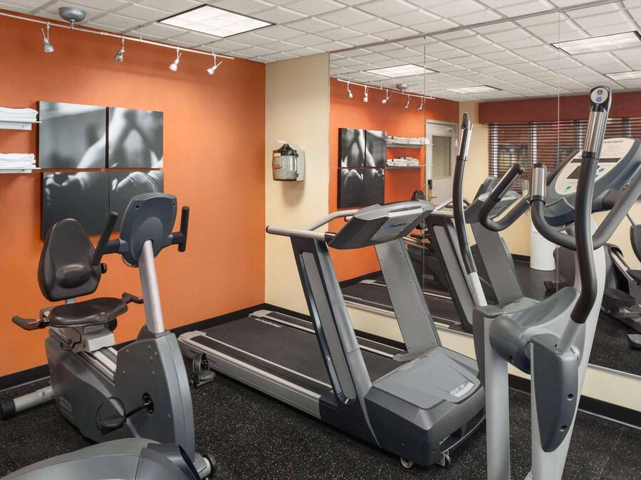 Un gimnasio con cintas de correr, bicicletas estáticas y un espejo grande.