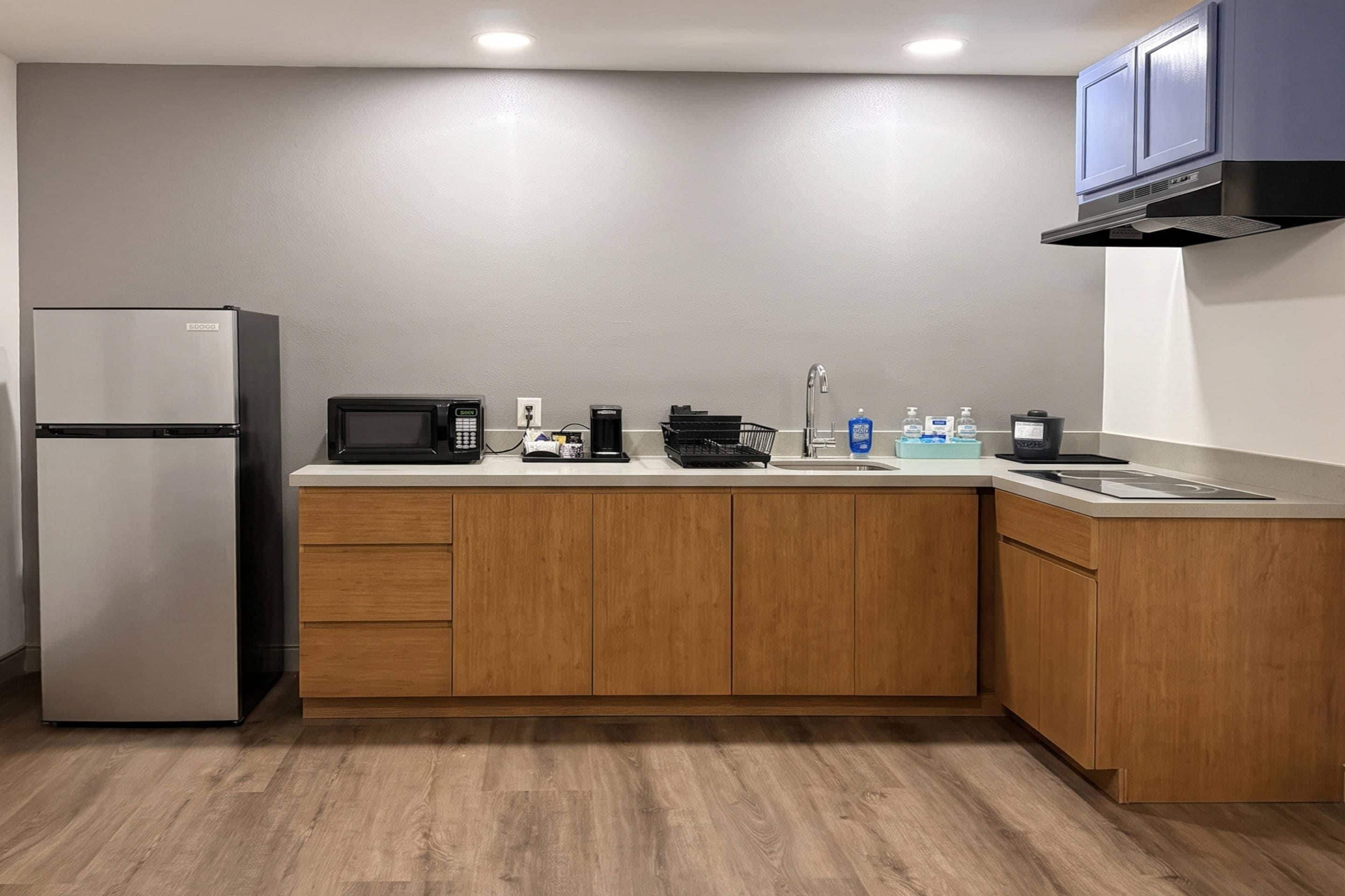 Una cocina compacta equipada con refrigerador, microondas, cafetera y pileta.