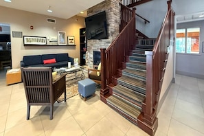 A living room with a fireplace, a staircase, and a sofa. - Country Inn & Suites by Radisson, Lima (Lima)