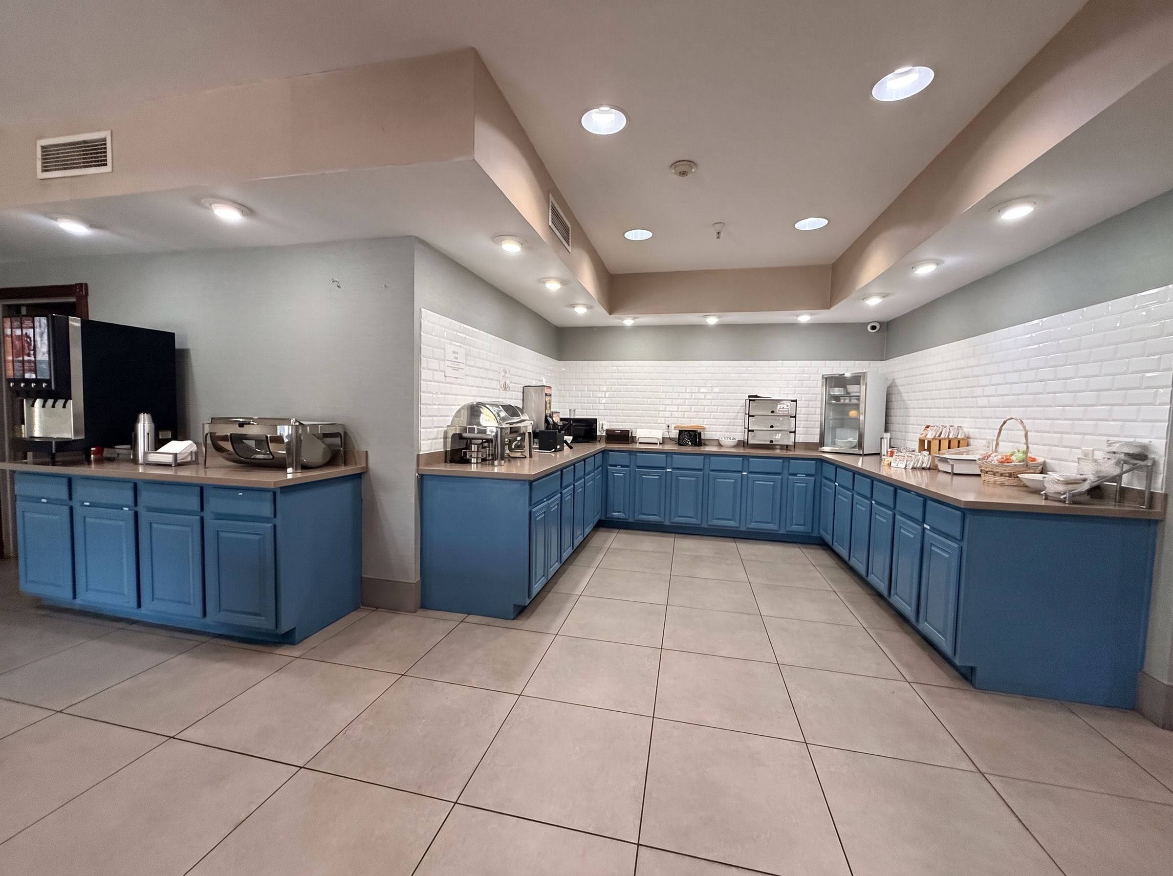Una cocina moderna con armarios azules, una isla central y un salpicadero blanco con azulejos.