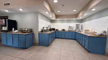 Una cocina moderna con armarios azules, una isla central y un salpicadero blanco con azulejos.