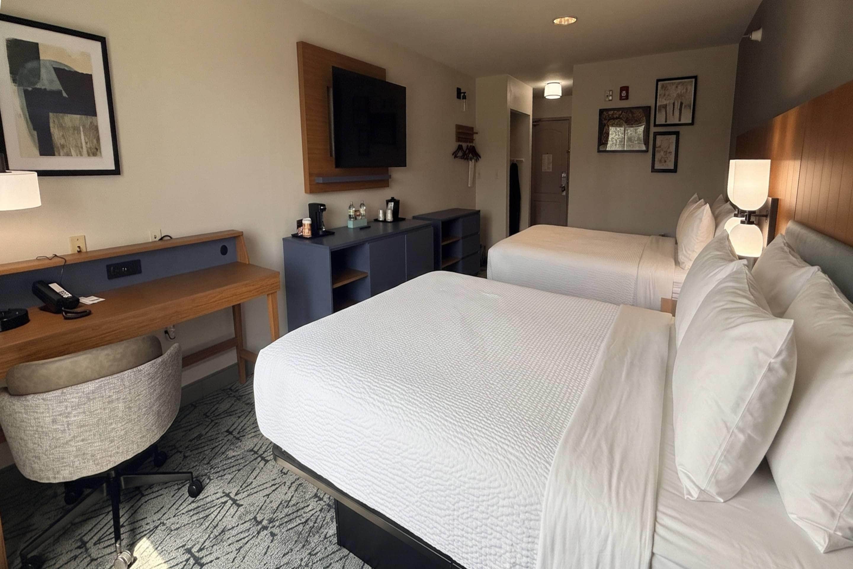 Ein Hotelzimmer mit einem Bett, einem Schreibtisch, einem Sessel, einem Fernseher und einem Kleiderschrank.