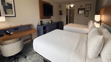 A hotel room with a bed, a desk, a chair, a television, and a wardrobe.