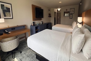 A hotel room with a bed, a desk, a chair, a television, and a wardrobe.