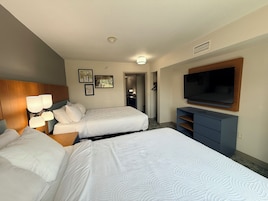 Habitación de hotel con dos camas, televisión, escritorio y armario.