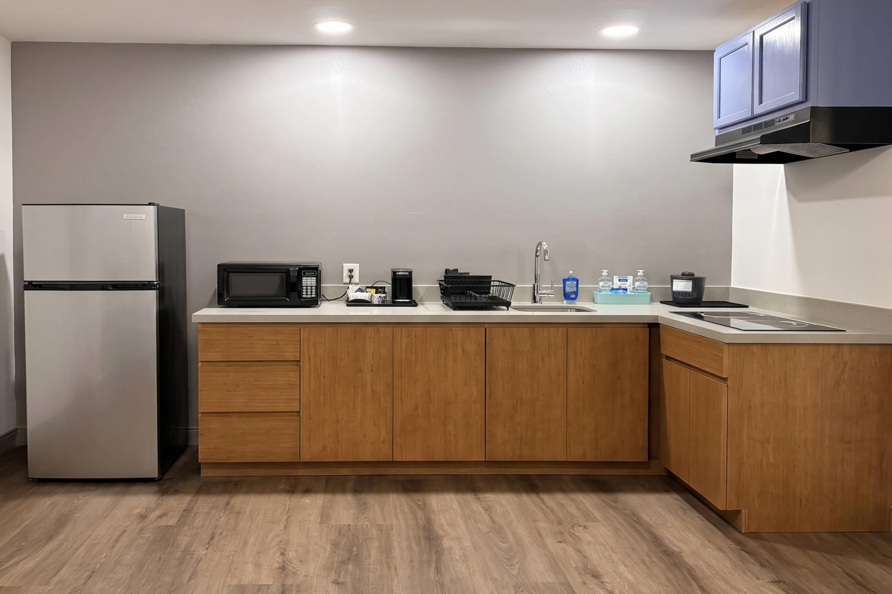 A compact kitchen with a refrigerator, microwave, coffee maker, and a sink.