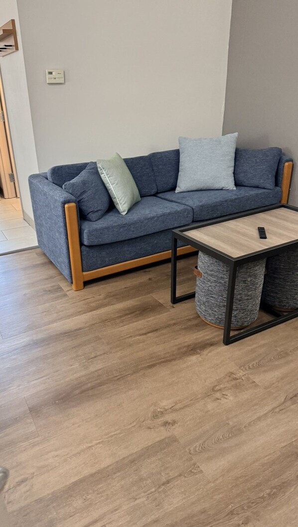 A modern living room with a grey sofa, a wooden coffee table, and a grey rug. - Country Inn & Suites by Radisson, Lima (Lima)