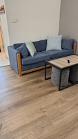 Una sala de estar moderna con un sofá gris, una mesa de centro de madera y una alfombra gris.