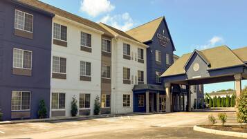 A multi-story hotel with a modern design, featuring a prominent entrance and a parking lot.