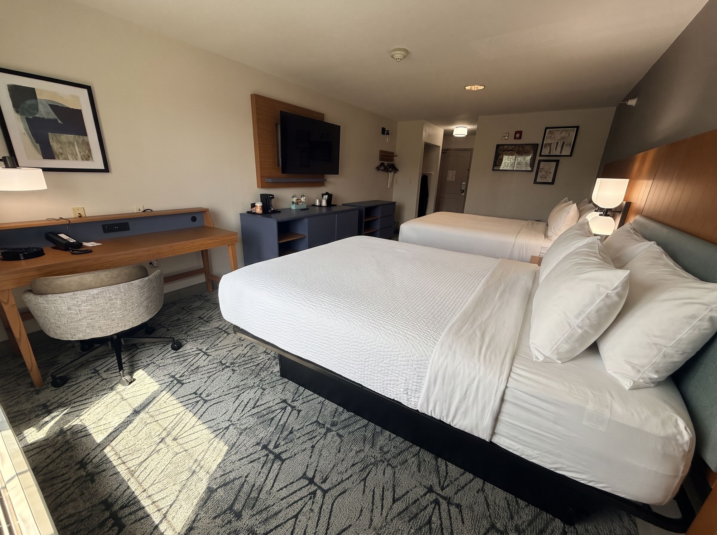 A hotel room with a large bed, a desk, a chair, a television, and a bathroom.